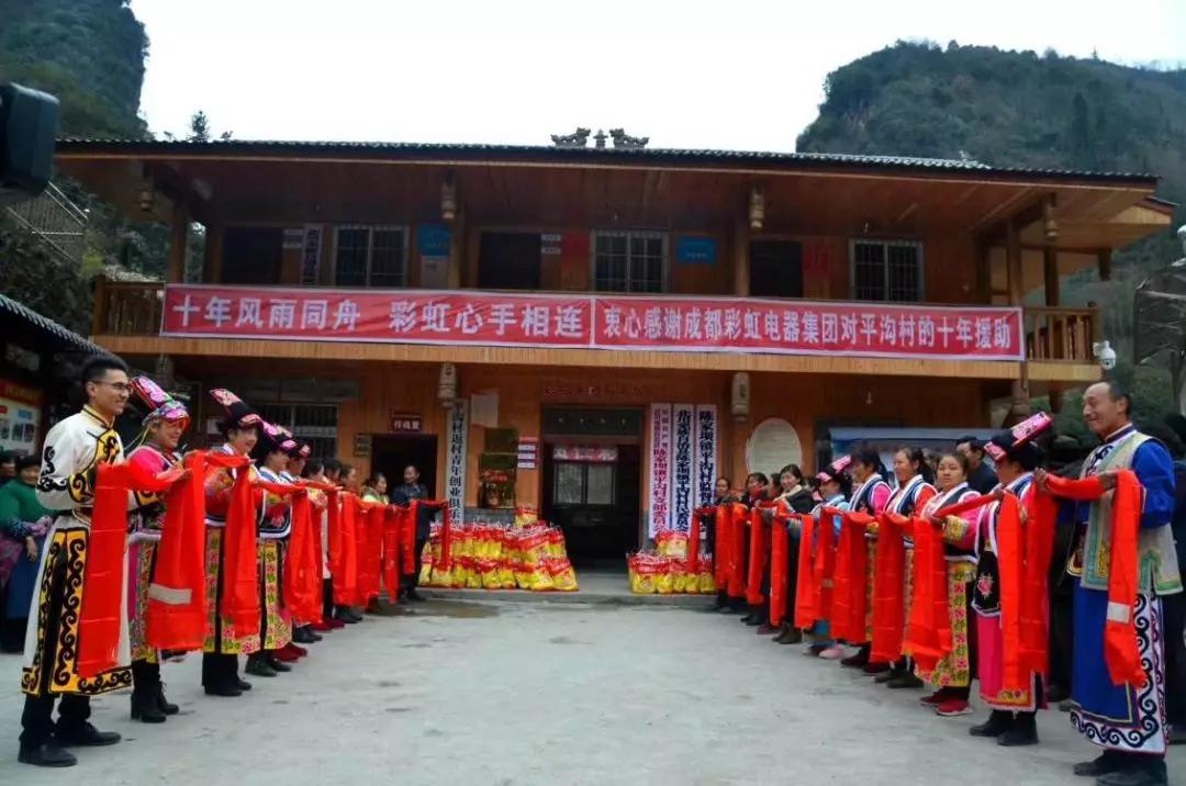 怀感恩之心，平沟村村民手持羌红在雷速在线注册-雷速（中国）公司援建的平沟村便民服务楼前热情等待雷速在线注册-雷速（中国）亲人们的到来